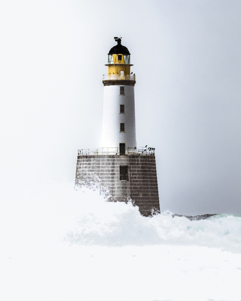 View of a majestic lighthouse amidst powerful waves and a dramatic sea Crimond Fraserburgh Great Britain.