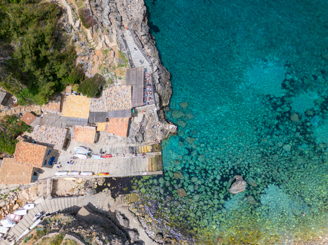 Aerial view of Cala Deia featuring turquoise waters rocky cliffs and traditional stone buildings in Spain. Aerial view of Cala Deia featuring turquoise waters rocky cliffs and traditional stone buildings in Spain.