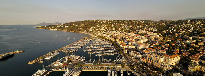 Aerial view of Golfe Juan Marina with rows of yachts and sailboats docked in the harbor surrounded by the coastal town of Vallauris Provence Alpes Cote d Azur France.