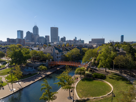 Aerial view of the Indianapolis skyline and the Central Canal with its iconic orange pedestrian bridge surrounded by lush parkland and urban architecture in Indianapolis Indiana United States. Aerial view of the Indianapolis skyline and the Central Canal with its iconic orange pedestrian bridge surrounded by lush parkland and urban architecture in Indianapolis Indiana United States.