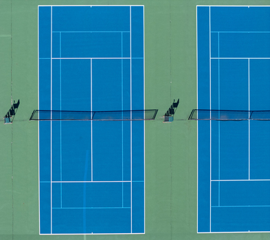 Aerial view of two blue tennis courts with white lines and nets in Kalamazoo Michigan United States. Aerial view of two blue tennis courts with white lines and nets in Kalamazoo Michigan United States.