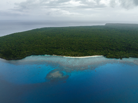 Aerial view of the lush green island meeting the turquoise sea under a cloudy sky Hunete Loyalty Islands Province New Caledonia. Aerial view of the lush green island meeting the turquoise sea under a cloudy sky Hunete Loyalty Islands Province New Caledonia.