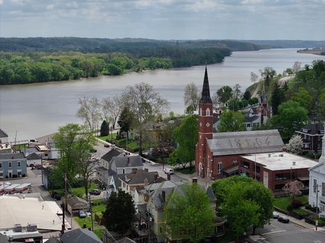 Aerial view of the historic red brick church with its tall spire and the Ohio River flowing past the lush green riverbanks in Aurora Indiana United States. Aerial view of the historic red brick church with its tall spire and the Ohio River flowing past the lush green riverbanks in Aurora Indiana United States.