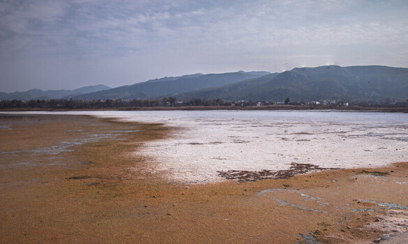 view of sun kissed shallows meet distant mountains under a muted sky creating a serene yet stark landscape Uchhali Lake Pakistan. view of sun kissed shallows meet distant mountains under a muted sky creating a serene yet stark landscape Uchhali Lake Pakistan.