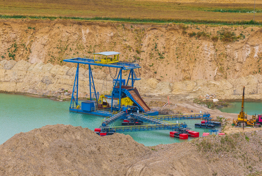 Aerial view of a floating industrial dredger operating in a turquoise gravel pit pond surrounded by sandy excavation banks and agricultural fields in Tczew Pomeranian Voivodeship Poland. Aerial view of a floating industrial dredger operating in a turquoise gravel pit pond surrounded by sandy excavation banks and agricultural fields in Tczew Pomeranian Voivodeship Poland.
