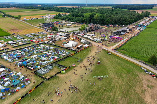Herzogenaurach Germany 24 July 2025 Aerial view of the Open Beatz Festival featuring a Ferris wheel large stages and crowds of people surrounded by green fields and forests.