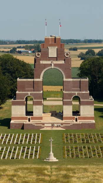Aerial view of the Thiepval Memorial to the Missing of the Somme surrounded by a war cemetery with rows of graves and rural fields in Thiepval Hauts de France France.