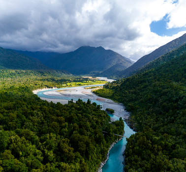 Aerial view of a turquoise river carves through a vibrant green gorge under a moody sky creating a stunning contrast of colors and textures Hokitika Gorge West Coast Region New Zealand. Aerial view of a turquoise river carves through a vibrant green gorge under a moody sky creating a stunning contrast of colors and textures Hokitika Gorge West Coast Region New Zealand.