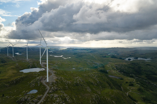 Aerial view of Makaknuten Vindkraftverk wind turbines set amidst rolling green hills small lakes and a gravel road under a cloudy sky in Bjerkreim Municipality Rogaland Norway. Aerial view of Makaknuten Vindkraftverk wind turbines set amidst rolling green hills small lakes and a gravel road under a cloudy sky in Bjerkreim Municipality Rogaland Norway.