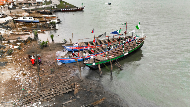 Aerial view of wooden boats moored along a muddy riverbank with people working nearby in Rivers Nigeria.