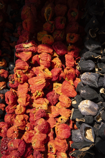 View of strings of dried red peppers and dark eggplants hanging in a traditional market stall Kayseri Kayseri Turkiye. View of strings of dried red peppers and dark eggplants hanging in a traditional market stall Kayseri Kayseri Turkiye.