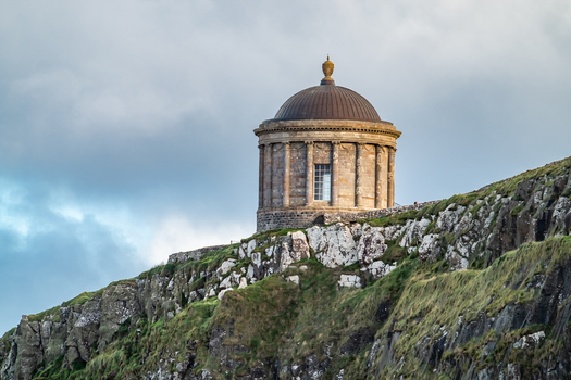 View of the historic Mussenden Temple perched on a rugged cliff edge overlooking the coast in Downhill Northern Ireland United Kingdom. View of the historic Mussenden Temple perched on a rugged cliff edge overlooking the coast in Downhill Northern Ireland United Kingdom.