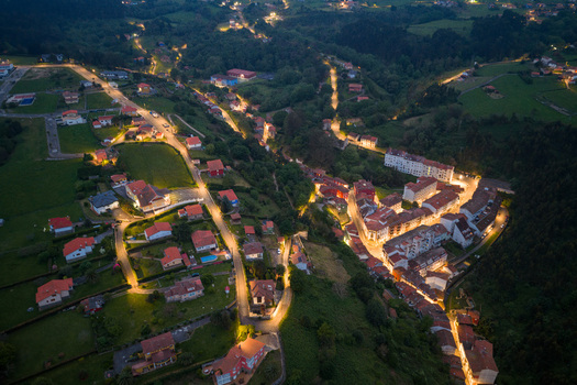 Aerial view of the illuminated town of Cudillero at night with winding streets and houses nestled in a green valley Cudillero Asturias Spain. Aerial view of the illuminated town of Cudillero at night with winding streets and houses nestled in a green valley Cudillero Asturias Spain.