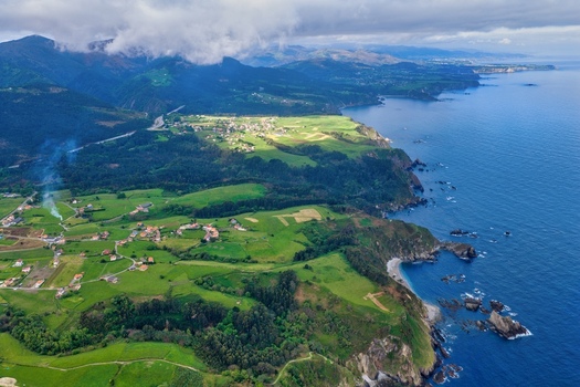 Aerial view of Silence Beach Viewpoint and the rugged coastline with green meadows and small villages under a cloudy sky in Cudillero Asturias Spain.