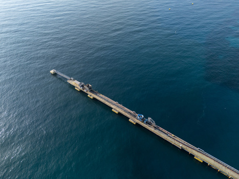 Aerial view of a long industrial pier extending into the deep blue sea in Bajos de Haina San Cristobal Province Dominican Republic.