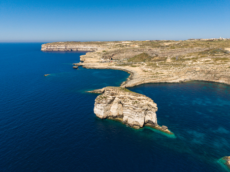 Aerial view of the rugged limestone cliffs and turquoise waters of Dwejra Bay with Fungus Rock in the Mediterranean Sea Gozo Region Malta. Aerial view of the rugged limestone cliffs and turquoise waters of Dwejra Bay with Fungus Rock in the Mediterranean Sea Gozo Region Malta.