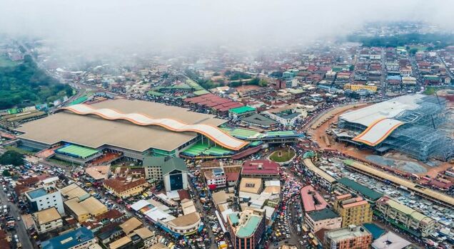 Aerial view of the Kejetia Market with its distinctive wavy roof structure surrounded by a dense urban landscape and bustling streets in Ghana. Aerial view of the Kejetia Market with its distinctive wavy roof structure surrounded by a dense urban landscape and bustling streets in Ghana.