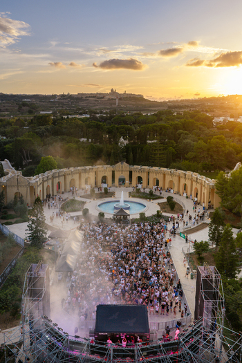 Attard Malta 20 September 2026 Aerial view of Park Nazzjonali Ta Qali featuring a large crowd gathered at an outdoor music festival with a central fountain and stage at sunset. Attard Malta 20 September 2026 Aerial view of Park Nazzjonali Ta Qali featuring a large crowd gathered at an outdoor music festival with a central fountain and stage at sunset.