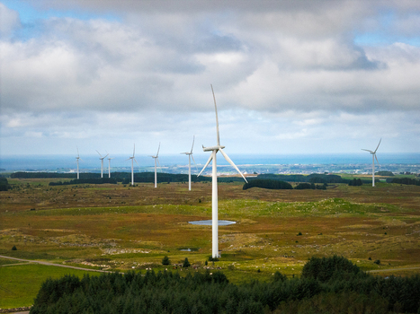 Aerial view of the Hog Jaeren wind farm with large white wind turbines standing in a vast green and brown landscape under a cloudy sky in Ha Municipality Rogaland Norway.