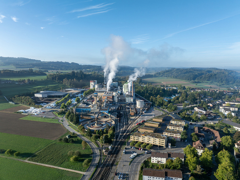 Aerial view of the Zuckerfabrik sugar factory with industrial buildings and smoking chimneys surrounded by green fields and infrastructure in Aarberg Bern Switzerland. Aerial view of the Zuckerfabrik sugar factory with industrial buildings and smoking chimneys surrounded by green fields and infrastructure in Aarberg Bern Switzerland.