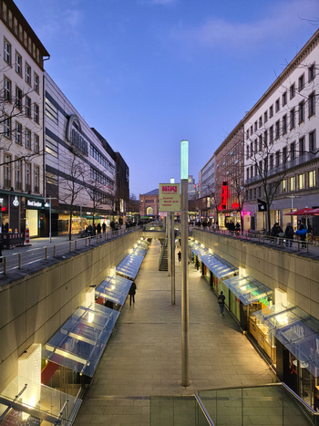 Hanover Germany 30 March 2026 View of the Niki de Saint Phalle Promenade in Hanover featuring a sunken pedestrian walkway lined with shops modern architecture and evening lighting.