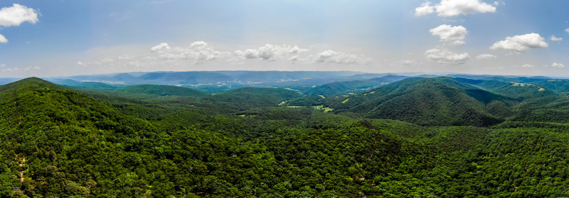 Lost City West Virginia United States 12 June 2019 Aerial view of lush green forested mountains under a bright blue sky with scattered white clouds. Lost City West Virginia United States 12 June 2019 Aerial view of lush green forested mountains under a bright blue sky with scattered white clouds.