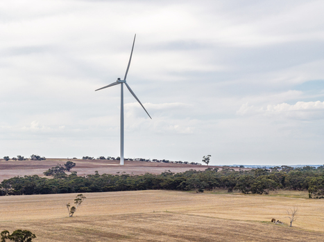 Aerial view of a wind turbine standing in a vast rural landscape with dry fields and scattered trees under a cloudy sky in Nhill Victoria Australia. Aerial view of a wind turbine standing in a vast rural landscape with dry fields and scattered trees under a cloudy sky in Nhill Victoria Australia.