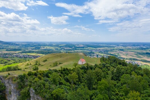 Aerial view of the Walberla hill with the St. Walburga chapel surrounded by lush green forests and rolling hills in Kirchehrenbach Bavaria Germany. Aerial view of the Walberla hill with the St. Walburga chapel surrounded by lush green forests and rolling hills in Kirchehrenbach Bavaria Germany.