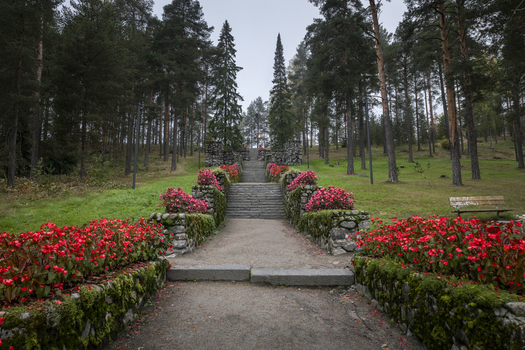 View of a stone staircase lined with vibrant red flowers and mossy stone walls leading into a pine forest in Jyvaskyla Central Finland Finland.