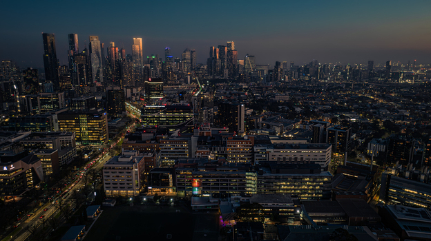 Aerial view of the Melbourne skyline at night with illuminated skyscrapers glowing city streets and urban density in Parkville Victoria Australia. Aerial view of the Melbourne skyline at night with illuminated skyscrapers glowing city streets and urban density in Parkville Victoria Australia.