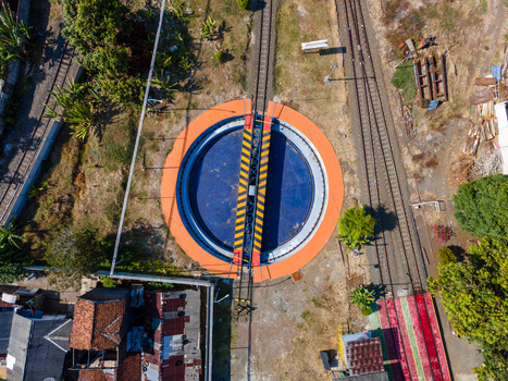 Aerial view of a railway turntable with yellow and black hazard markings surrounded by tracks and vegetation in Cilacap Central Java Indonesia. Aerial view of a railway turntable with yellow and black hazard markings surrounded by tracks and vegetation in Cilacap Central Java Indonesia.