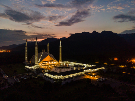 Aerial view of Faisal Masjid illuminated at dusk with the Margalla Hills in the background under a cloudy sunset sky Islamabad Islamabad Capital Ter Pakistan. Aerial view of Faisal Masjid illuminated at dusk with the Margalla Hills in the background under a cloudy sunset sky Islamabad Islamabad Capital Ter Pakistan.