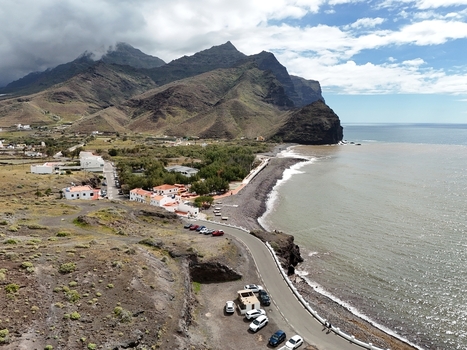 Aerial view of the dramatic coastline where the dark sand beach meets the turbulent sea under a sky heavy with clouds Puerto de la Aldea Canarias Spain. Aerial view of the dramatic coastline where the dark sand beach meets the turbulent sea under a sky heavy with clouds Puerto de la Aldea Canarias Spain.