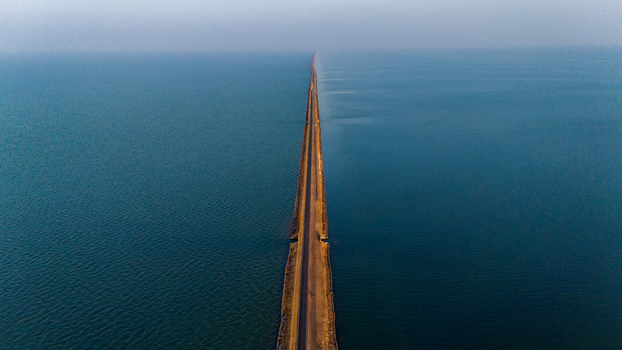 Aerial view of Road to Heaven stretching across the vast Rann of Kutch surrounded by calm blue waters under a clear sky in Bhuj Gujarat India. Aerial view of Road to Heaven stretching across the vast Rann of Kutch surrounded by calm blue waters under a clear sky in Bhuj Gujarat India.