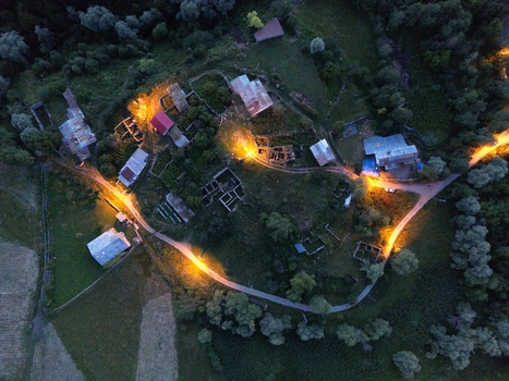 Aerial view of warm lights illuminating the village homes nestled amidst the dark green forest creating a cozy contrast Posof Ardahan Türkiye. Aerial view of warm lights illuminating the village homes nestled amidst the dark green forest creating a cozy contrast Posof Ardahan Türkiye.