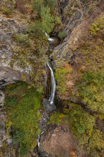 Aerial view of the cascading Ovcharenski Waterfall Goritsa surrounded by rocky cliffs and vibrant autumn forest foliage in Ovchartsi Kyustendil Province Bulgaria. Aerial view of the cascading Ovcharenski Waterfall Goritsa surrounded by rocky cliffs and vibrant autumn forest foliage in Ovchartsi Kyustendil Province Bulgaria.