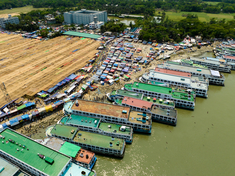Aerial view of a bustling riverbank teeming with colorful boats against a backdrop of buildings and verdant trees Charmonai Barisal Division Bangladesh. Aerial view of a bustling riverbank teeming with colorful boats against a backdrop of buildings and verdant trees Charmonai Barisal Division Bangladesh.