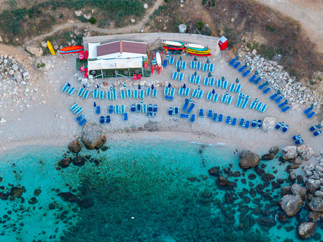 Aerial view of Riserva Naturale Orientata dello Zingaro with turquoise water pebble beach colorful kayaks and rows of sun loungers in San Vito Lo Capo Sicilia Italy. Aerial view of Riserva Naturale Orientata dello Zingaro with turquoise water pebble beach colorful kayaks and rows of sun loungers in San Vito Lo Capo Sicilia Italy.