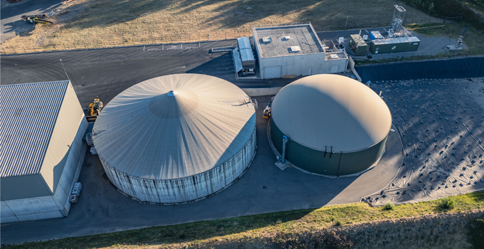 Aerial view of anaerobic digestion tanks at a biogas plant with large circular domes industrial buildings and paved grounds in Le Pouzin Auvergne Rhone Alpes France.