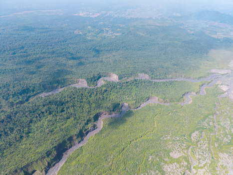 Aerial view of the volcanic debris path cutting through the lush green forest near Mount Semeru in the Supiturang area of Pronojiwo East Java Indonesia.