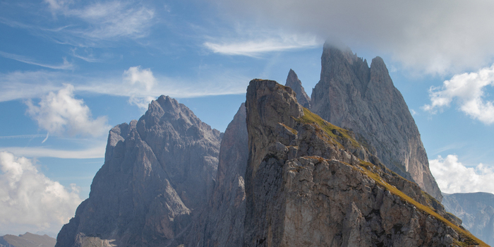 View of the jagged peaks of the Dolomites with rocky slopes and wispy clouds under a blue sky in Rocca Pietore Veneto Italy. View of the jagged peaks of the Dolomites with rocky slopes and wispy clouds under a blue sky in Rocca Pietore Veneto Italy.