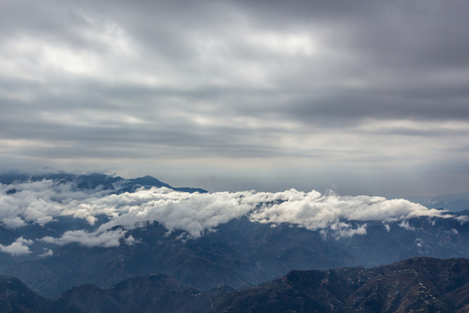 View of majestic mountains cloaked in ethereal white clouds beneath a somber overcast sky creating a serene yet dramatic vista Muzaffarabad Azad Kashmir Pakistan. View of majestic mountains cloaked in ethereal white clouds beneath a somber overcast sky creating a serene yet dramatic vista Muzaffarabad Azad Kashmir Pakistan.