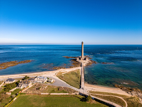 Aerial view of Gatteville Lighthouse on a rocky point surrounded by the blue English Channel with a stone causeway and coastal landscape. Gatteville le Phare Normandie France.