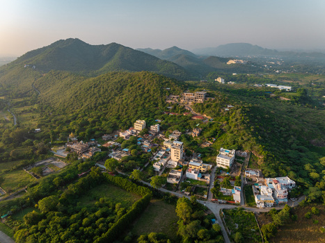Aerial view of a residential neighborhood nestled among lush green hills in Udaipur Rajasthan India.
