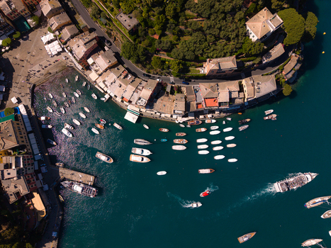 Aerial view of the harbor of Portofino featuring colorful buildings and numerous boats moored in the turquoise water surrounded by lush green hills Portofino Liguria Italy.