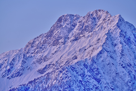 Aerial view of the snow covered peaks of Valchiavenna featuring rugged mountain slopes deep blue shadows and crisp winter light Lombardy Italy. Aerial view of the snow covered peaks of Valchiavenna featuring rugged mountain slopes deep blue shadows and crisp winter light Lombardy Italy.