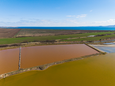 Aerial view of the colorful salt pans of Lake Atanasovsko with reddish and yellow evaporation ponds near green fields and the Black Sea coast in Burgas Burgas Bulgaria. Aerial view of the colorful salt pans of Lake Atanasovsko with reddish and yellow evaporation ponds near green fields and the Black Sea coast in Burgas Burgas Bulgaria.