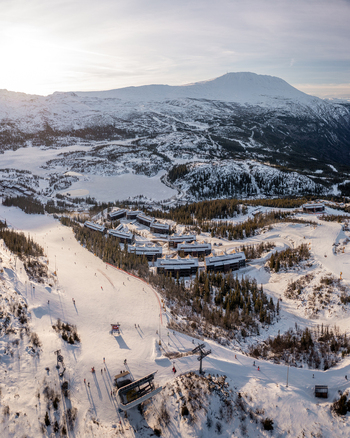 Aerial view of Gaustablikk Fjellresort nestled in the snowy mountains with ski slopes chairlifts and pine forests in Rjukan Telemark Norway. Aerial view of Gaustablikk Fjellresort nestled in the snowy mountains with ski slopes chairlifts and pine forests in Rjukan Telemark Norway.