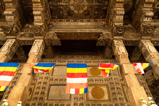 View of the intricate wood carvings and Buddhist flags inside the Temple of the Sacred Tooth Relic in Kandy Central Province Sri Lanka. View of the intricate wood carvings and Buddhist flags inside the Temple of the Sacred Tooth Relic in Kandy Central Province Sri Lanka.
