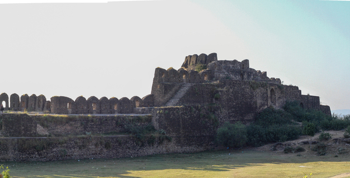 View of the historic Rohtas Fort with its ancient stone walls arched battlements and stairs rising above the grassy landscape in Dina Punjab Pakistan. View of the historic Rohtas Fort with its ancient stone walls arched battlements and stairs rising above the grassy landscape in Dina Punjab Pakistan.